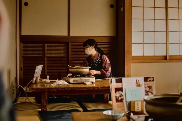 A Japanese man happily bites into a golden-brown crispy pork cutlet, while admiring the serene beauty of a traditional Japanese garden setting