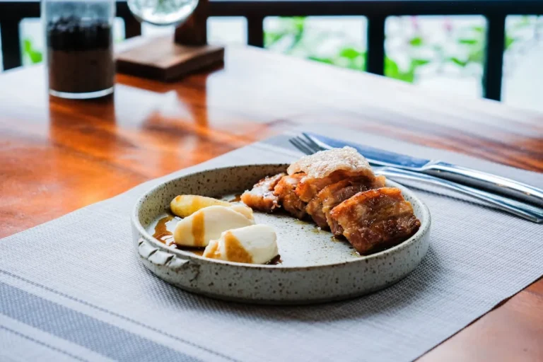A stunning close-up photograph of a perfectly fried pork cutlet, bathed in golden sunlight with a crispy exterior and juicy interior, on a traditional Japanese plate against a backdrop of blurred mountains.