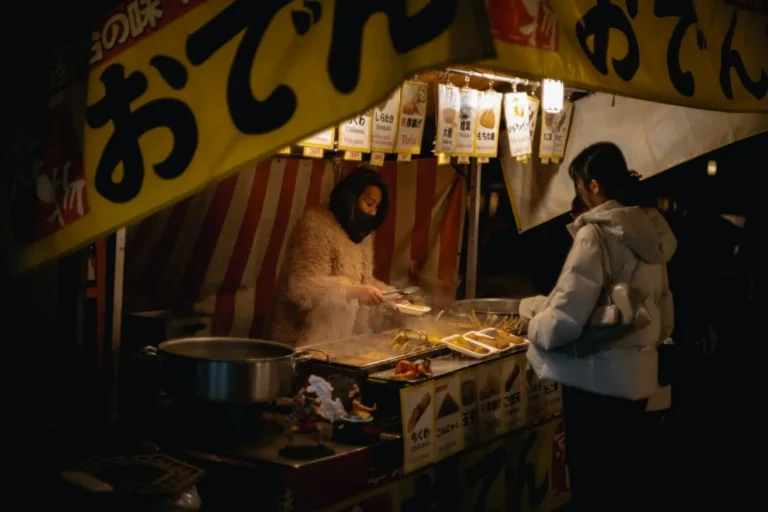 A vibrant street food scene unfolds in Japan, with a mouthwatering crispy pork cutlet resting atop colorful vegetables, bathed in warm streetlights. Capture the deliciousness of Japanese street food in this stunning close-up.